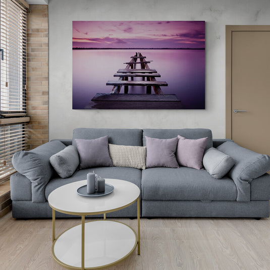 Muelle de madera antiguo al atardecer con cielo púrpura reflejado en agua tranquila