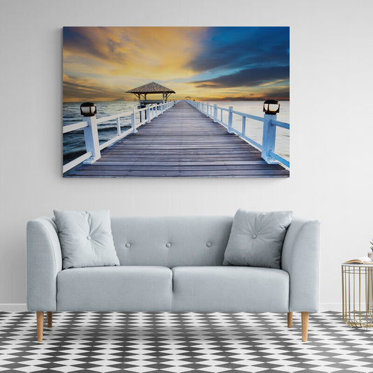 Fotografía de un muelle de madera con farolas y un techo de paja al atardecer con cielo dramático