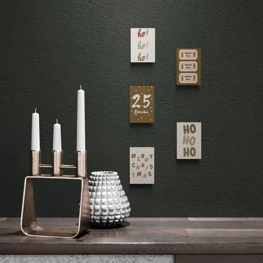 Lienzos navideños modernos con frases festivas y decoración metálica minimalista.