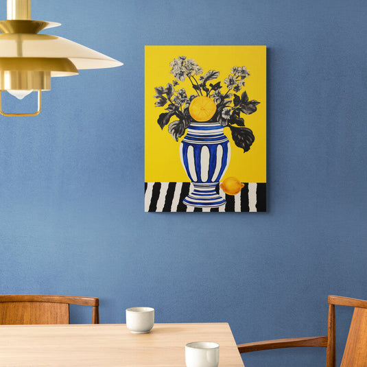 Naturaleza muerta vibrante con un jarrón a rayas, flores en blanco y negro, y un limón sobre fondo amarillo.