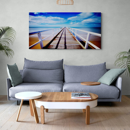 Fotografía de larga exposición de un muelle largo sobre playa tranquila hacia el cielo azul