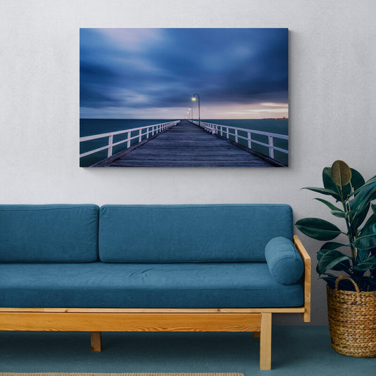Muelle de madera con farolas encendidas bajo un cielo nublado al amanecer.