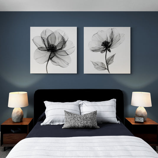 "Dos cuadros monocromáticos de grandes flores sobre un fondo oscuro en un elegante dormitorio con iluminación suave y decoración minimalista.