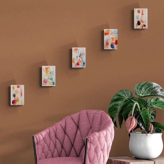 Conjunto de cuadros geométricos abstractos en tonos cálidos sobre pared marrón