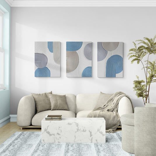 Tríptico decorativo abstracto con texturas en relieve y formas circulares en tonos azul pastel, gris y beige sobre fondo blanco