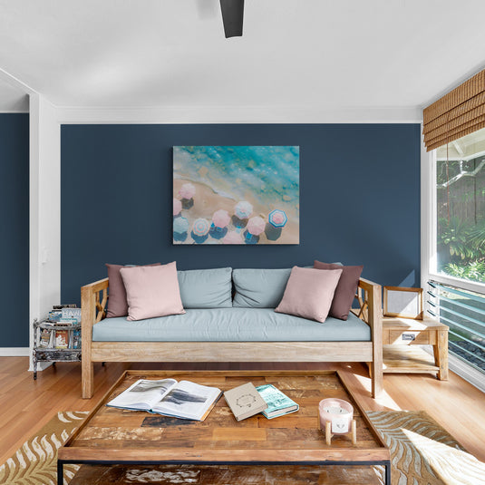 Cuadro de vista aérea de sombrillas pastel en una playa junto al mar turquesa.