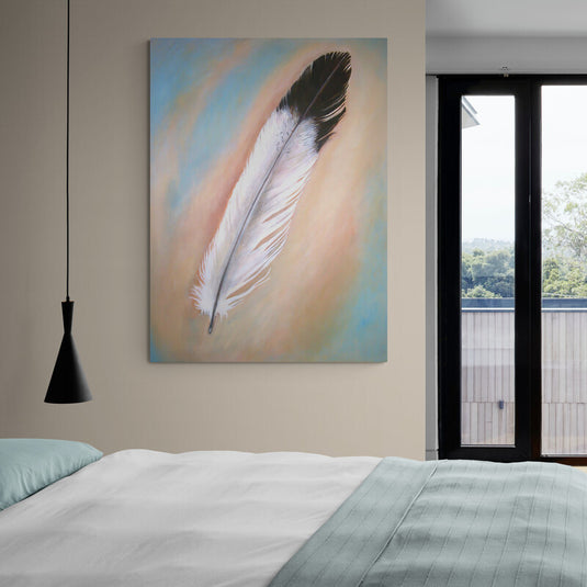 Pluma blanca con puntas negras sobre un vibrante fondo azul y naranja: una composición armónica de contrastes