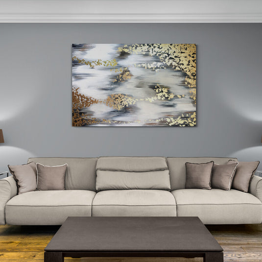 Cuadro abstracto con tonos dorados y plateados en una sala de estilo moderno y minimalista.