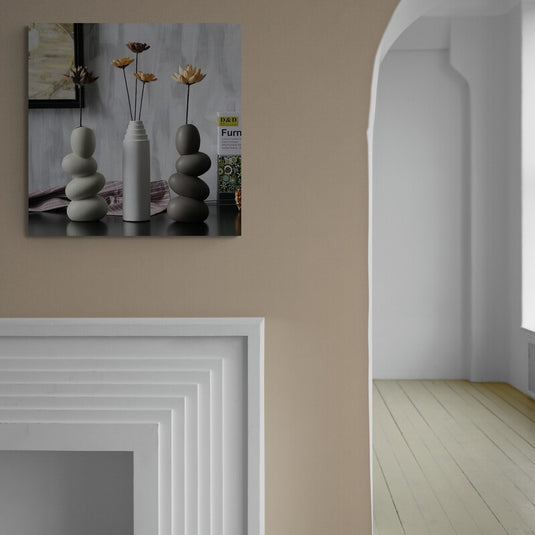 Composición minimalista con jarrón blanco y piedras apiladas en equilibrio