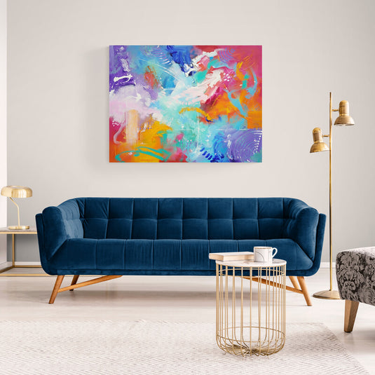 Cuadro abstracto en tonos azules, naranjas y rosas sobre sofá azul en sala moderna