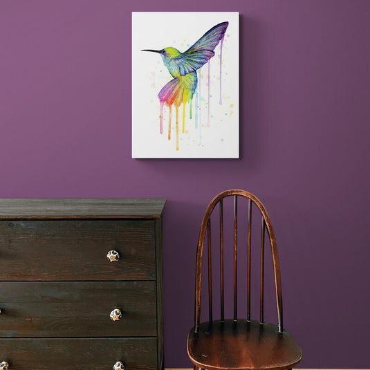 Cuadro decorativo con fondo blanco y colibrí en vuelo con tonos verde, azul, morado, rosa y amarillo, diseño de colores en efecto derretido.