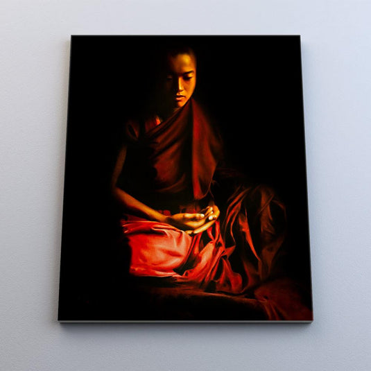 Retrato de un joven monje budista en meditación con túnica roja y fondo oscuro.