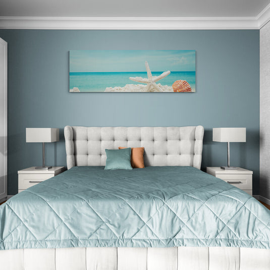 Cuadro de estrella de mar y concha en playa sobre cama en dormitorio azul