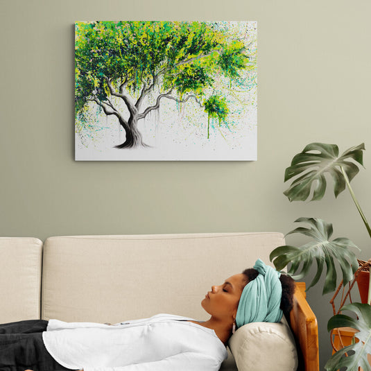 Cuadro decorativo con tronco gris y ramas con hojas verdes sobre fondo blanco.