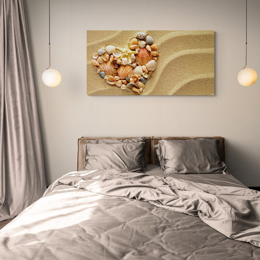 Corazón formado por conchas marinas variadas en arena clara con ondulaciones naturales