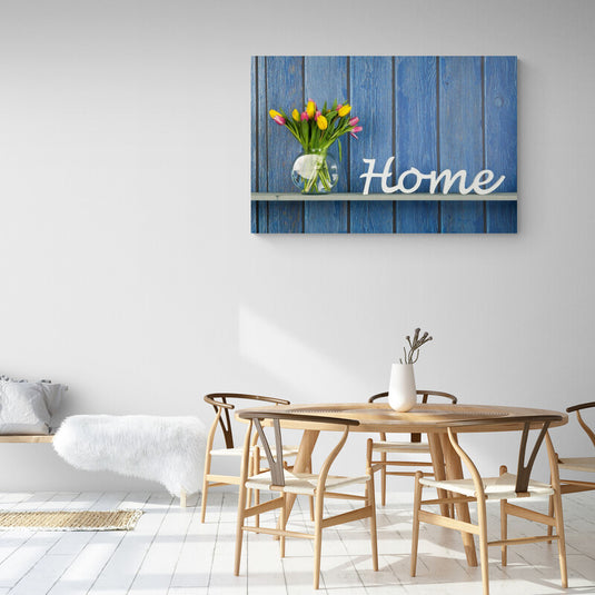 Jarrón con tulipanes multicolores y letrero de 'Home' sobre fondo de madera azul