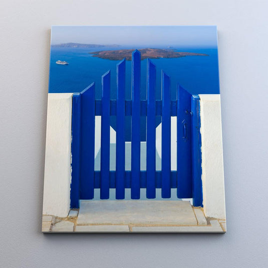 Puerta azul que se abre hacia una vista del mar y una isla, reflejando el estilo arquitectónico de las islas griegas