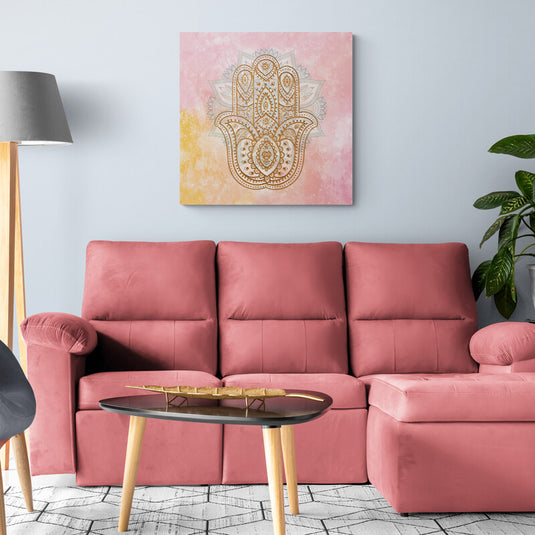 Mano de Hamsa dorada con fondo en tonos pastel rosa y amarillo.