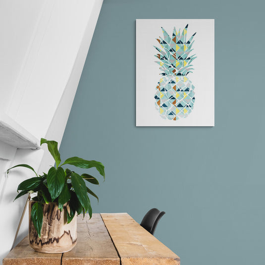 Cuadro geométrico de piña en pared azul con planta decorativa a un lado