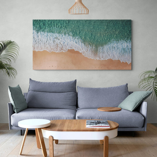 Vista aérea de la frontera entre el mar turquesa y la playa de arena con espuma blanca.