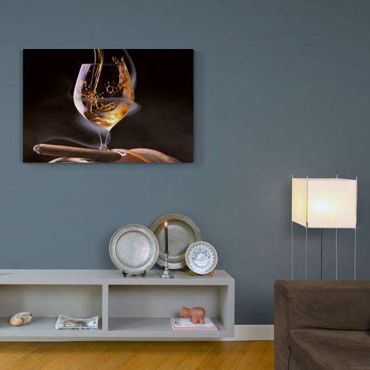 Copa con líquido dorado vertiéndose y puro encendido sobre fondo oscuro