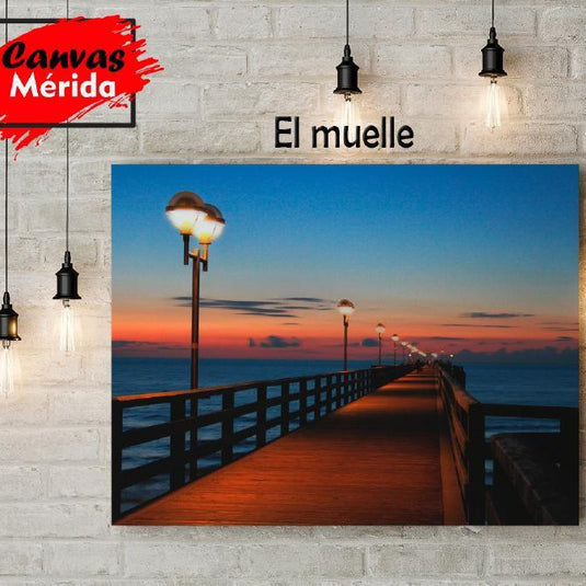 Vista nocturna de un muelle iluminado al atardecer sobre el mar.