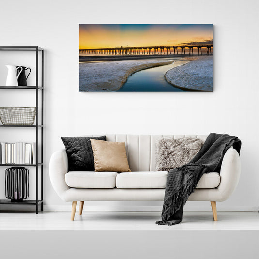 Fotografía del atardecer con un muelle largo y reflejos en el agua serena