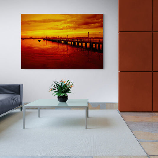 Fotografía de muelle con cielo y agua reflejando tonos de rojo y amarillo del atardecer