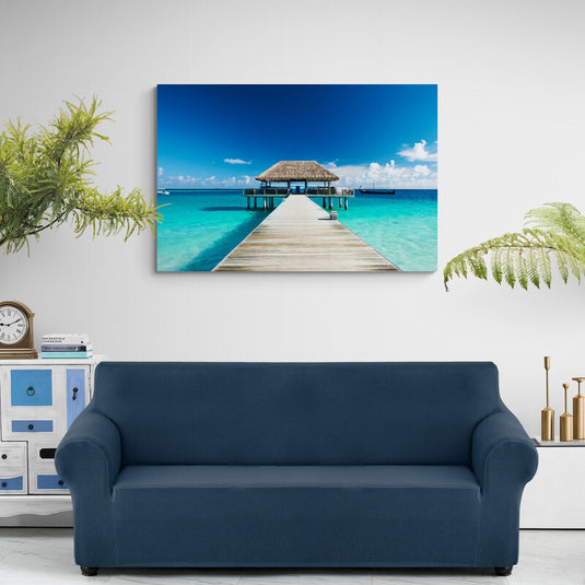 Fotografía de un muelle de madera que lleva a una cabaña sobre agua turquesa