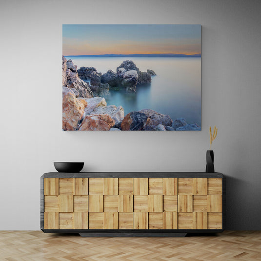 Fotografía de larga exposición de rocas en un mar calmado al amanecer o atardecer