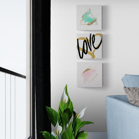 Set de cuadros minimalistas con fondo blanco: triángulo verde turquesa con borde dorado, corazón dorado con 'LOVE' central en negro, y rombo rosa con contorno dorado.