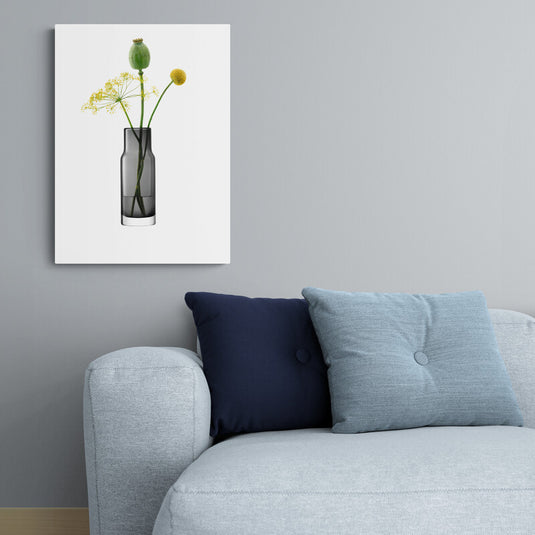 Florero negro de cristal con flores verdes y amarillas sobre fondo blanco