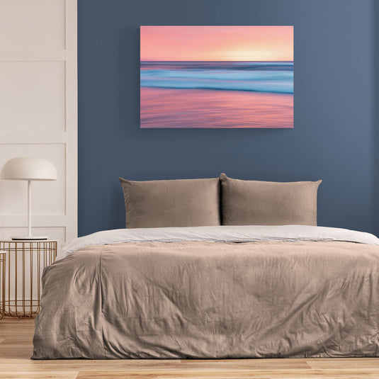 Fotografía de larga exposición con olas en tonos azules y cielo rosado al atardecer