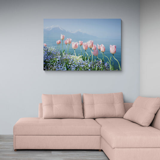 Tulipanes rosados frente a un lago con montañas nevadas al fondo.