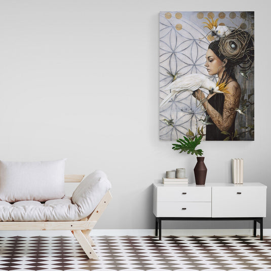 Mujer de perfil con vestido negro, diseño floral y tatuajes, nido en cabello con pájaro y huevo, sosteniendo guacamaya blanca