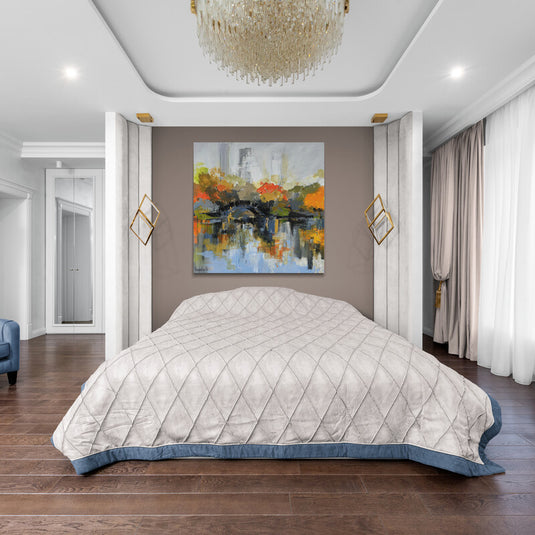 Cuadro de paisaje urbano con reflejos otoñales decorando un dormitorio elegante con paredes neutras.