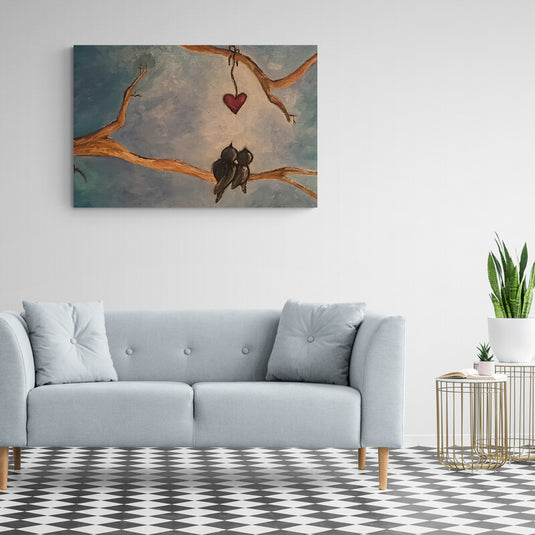 Cuadro decorativo con fondo azul pálido y detalles en crema, corazón rojo colgando de rama desnuda y dos pajaritos negros posados en ramita