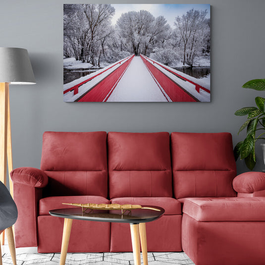 Puente invernal cubierto de nieve con toques rojos, rodeado de agua y árboles nevados