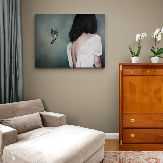Chica de espaldas con cabello negro y blusa caída en fondo oscuro, pajarito tirando del cordón de la blusa