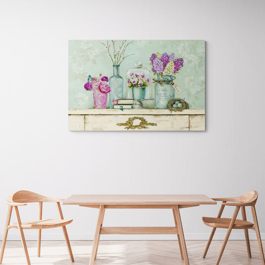 Flores en jarrones vintage sobre repisa con libros y nido de pájaros.