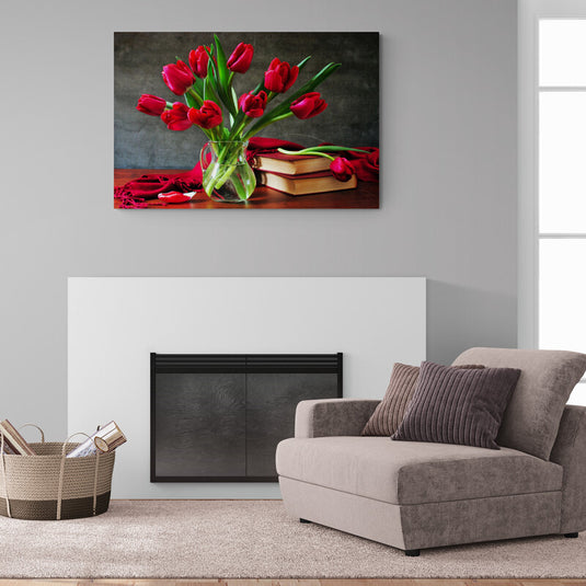 Ramo de tulipanes rojos en jarrón junto a libros y paño rojo