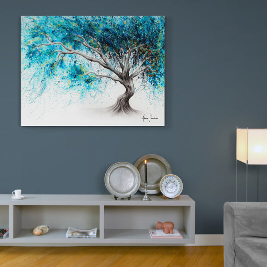 Cuadro decorativo con tronco de árbol en forma de mujer inclinada y ramas con hojas verdes sobre fondo blanco.