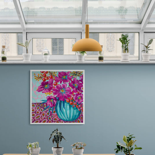 Ramillete de flores fucsia en jarrón turquesa sobre fondo y mantel colorido