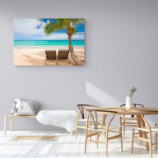 Dos sillas de playa bajo una palmera con el mar turquesa en el fondo