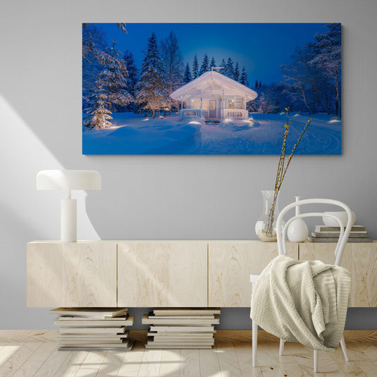 Cuadro_decorativo_fotográfico_de_casa_iluminada_rodeada_de_pinos_en_un_paisaje_nevado_al_anochecer