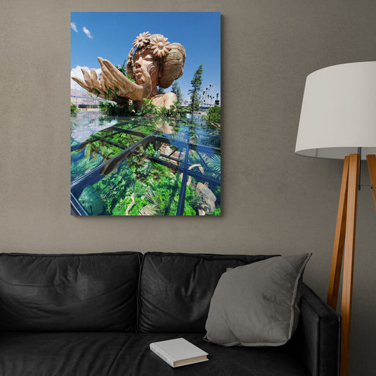 Escultura monumental de Madre Naturaleza con adornos florales y reflejo en un cristal rodeado de vegetación.