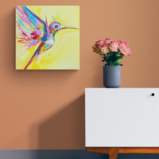 Cuadro decorativo con colibrí estilizado en tonos rosa, morado, rojo, verde, azul y naranja sobre fondo amarillo