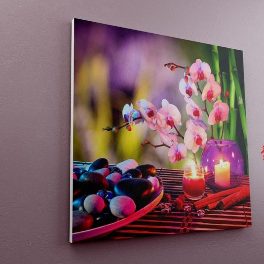 Escena zen con orquídeas blancas, vela encendida, guijarros y tallos de bambú.