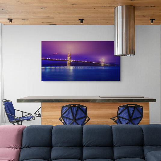 Fotografía del puente iluminado en crepúsculo con cielo púrpura y reflejos azules en el agua