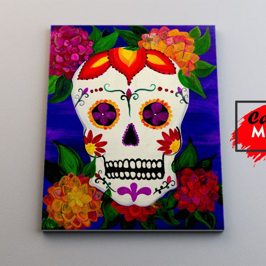 Cráneo de azúcar pintado con flores vibrantes en celebración del Día de Muertos sobre fondo azul